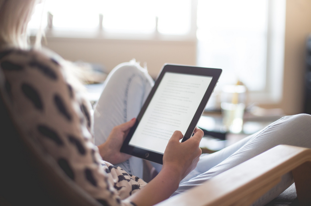 woman sitting in a chair holding an e-reader