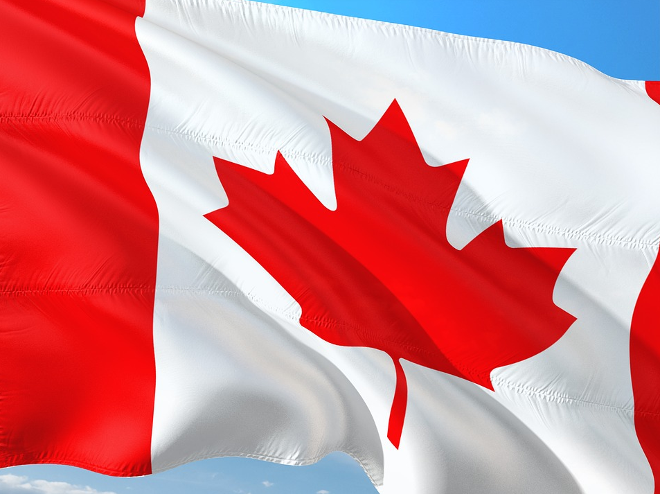 Red and white Canadian maple leaf flag against a blue sky