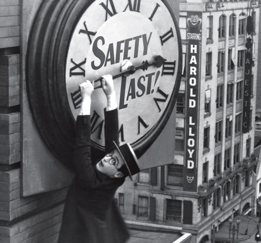 Photo of Harold Lloyd hanging from a clock face in the silent film Safety Last