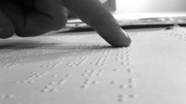 black and white photo of a person's finger reading Braille