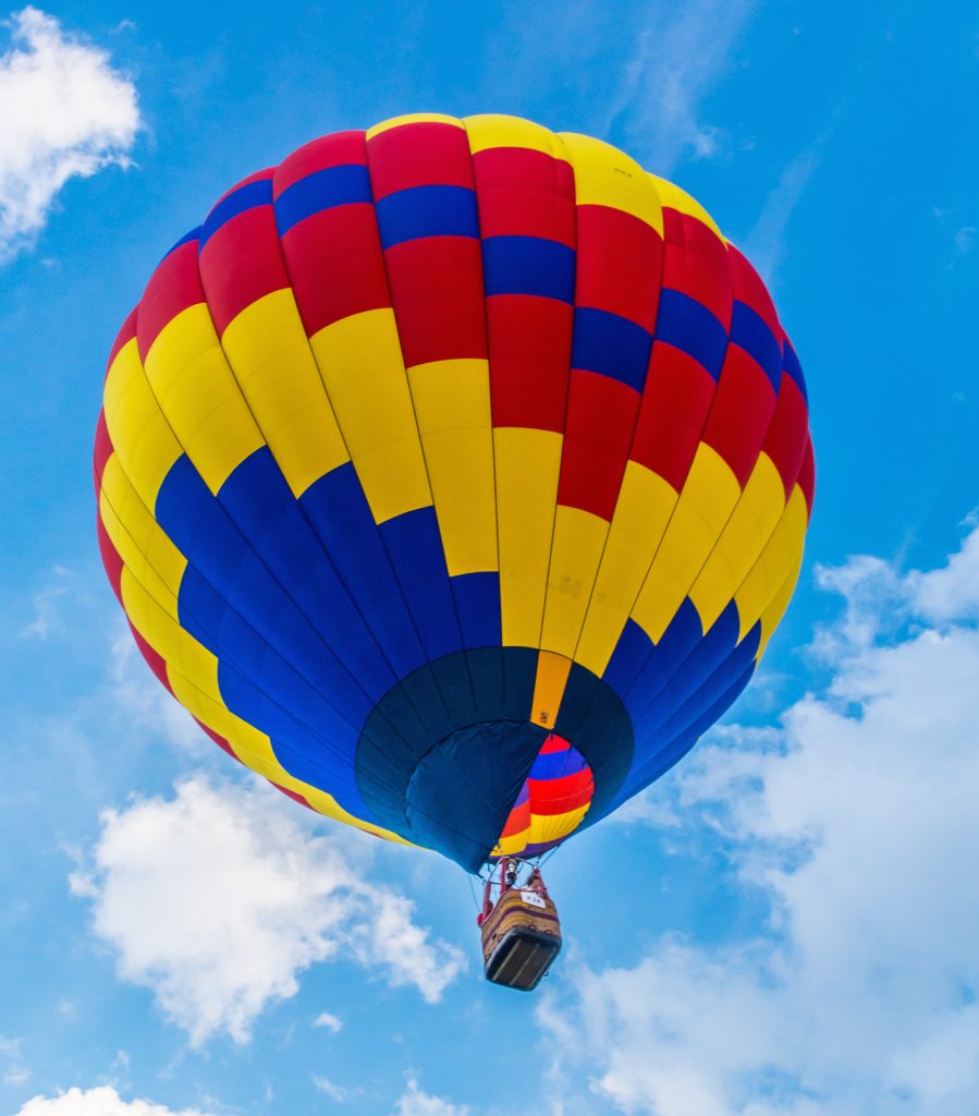 photo of a red, yellow, and blue hot air balloon against a blue sky