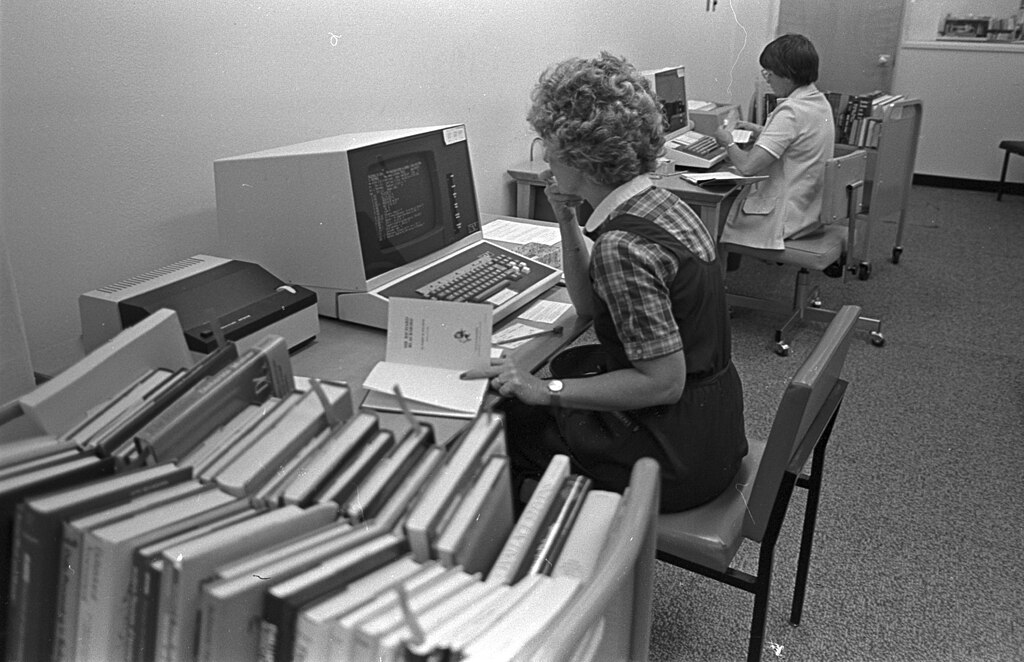 Woman working on an early computer in a library at University of Texas