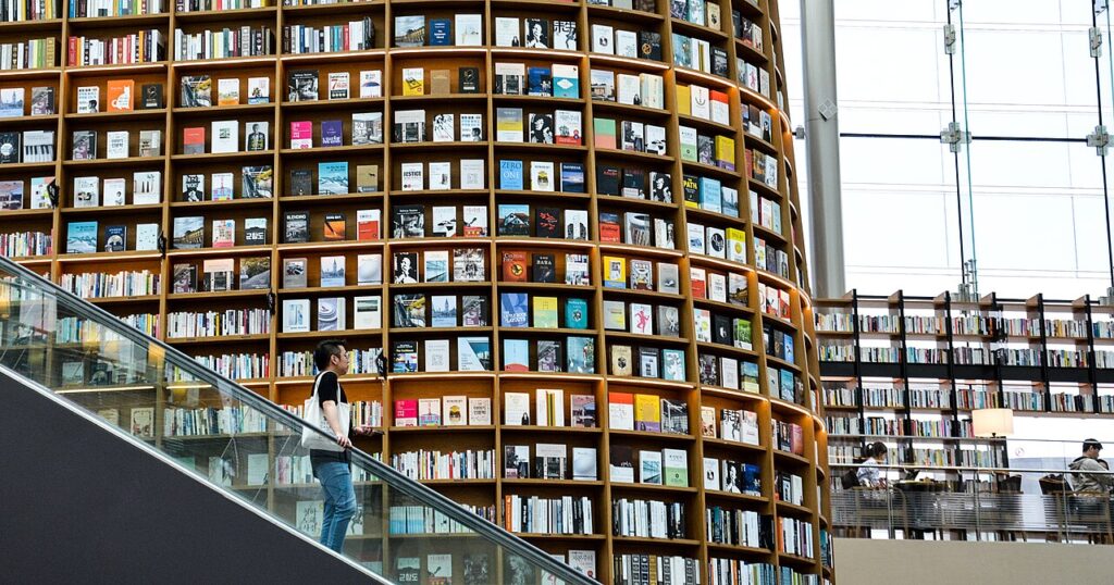 Large open room with large book display and man on an escalator